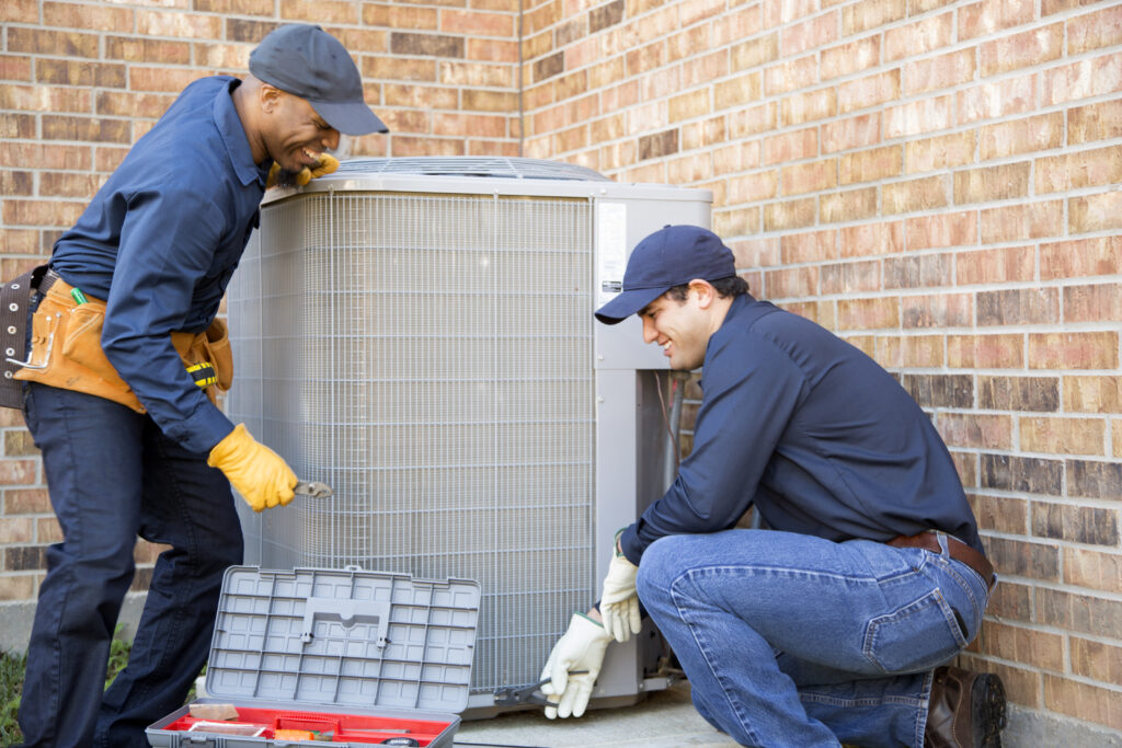 HVAC technicians repairing condenser unit